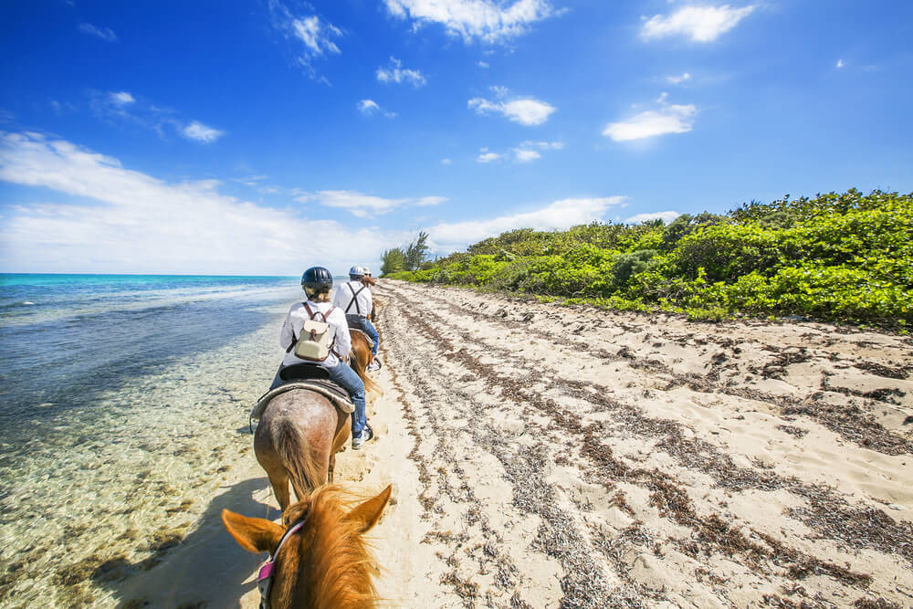 Photo of people horseback riding in Aruba at the beach