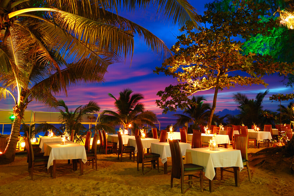 Tables set up at Aruba restaurants on the beach at sunset